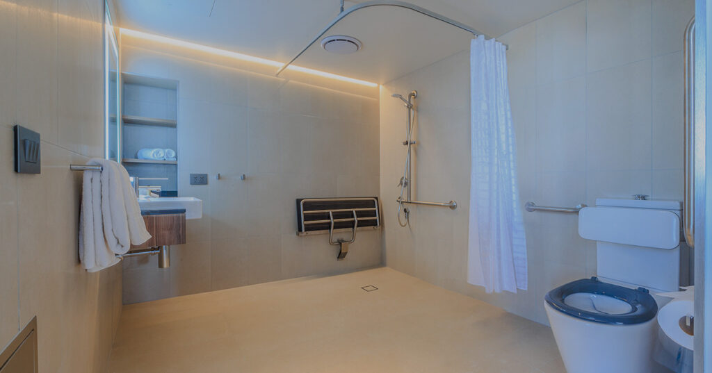 Roll-in shower bathroom at Wrest Point with grab rails, curtain and fold-down bench