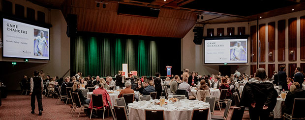 Interior of the Tasman Room at Wrest Point Hotel, with round tables and audiovisual projectors for a presentation.
