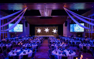 Interior of the Tasman Room at Wrest Point Hotel, set up with round tables, candles and a grand main stage.