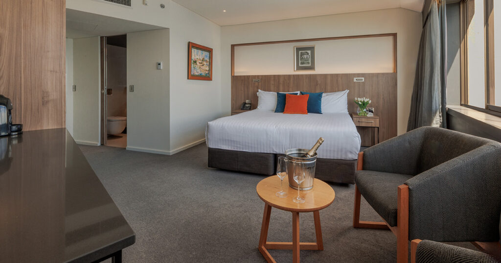 Spacious Harbour View Deluxe King at Wrest Point with king bed, seating area and large windows